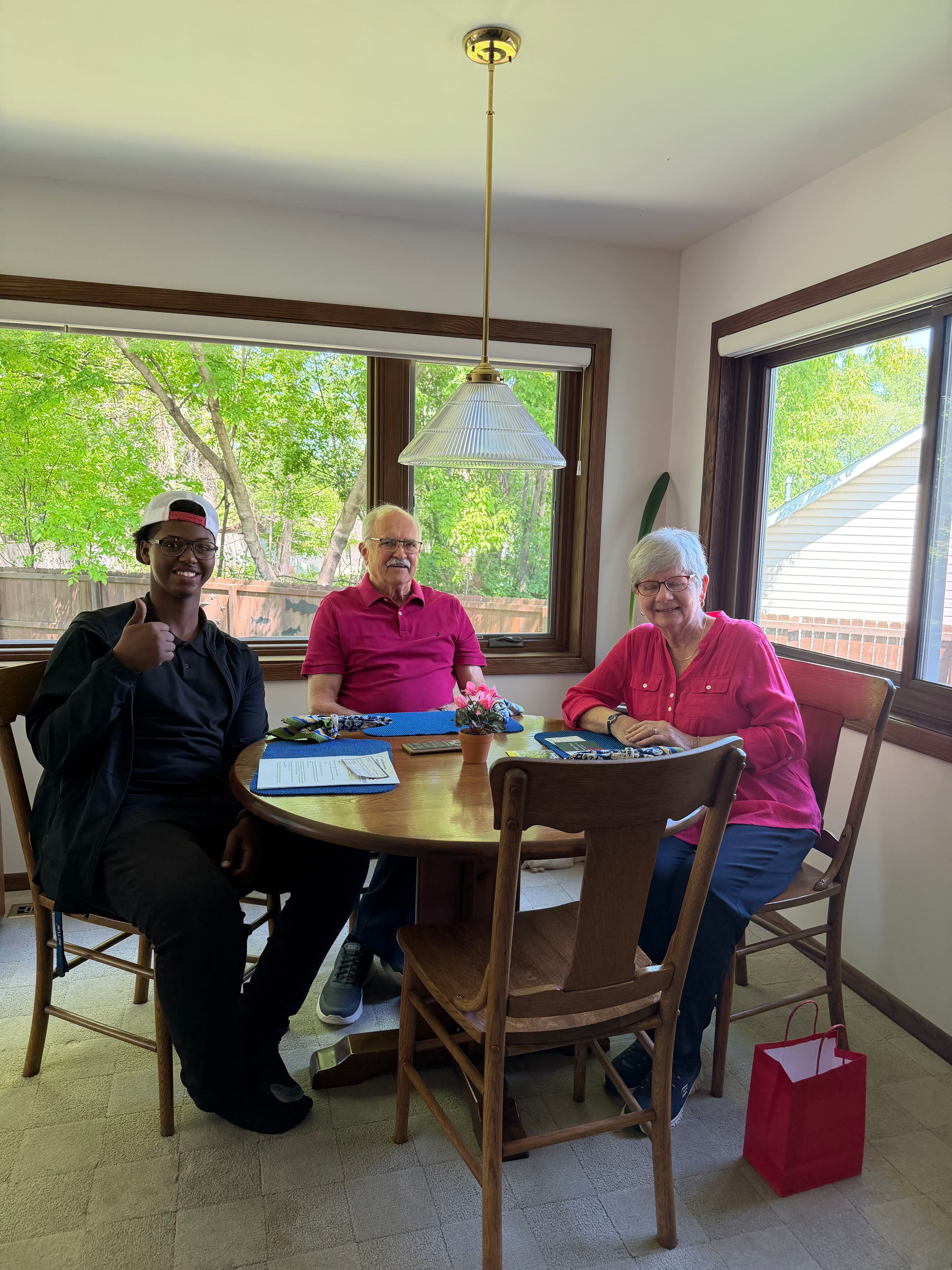 Family gathering at a dining table with two seniors and a young man, enjoying quality time together.